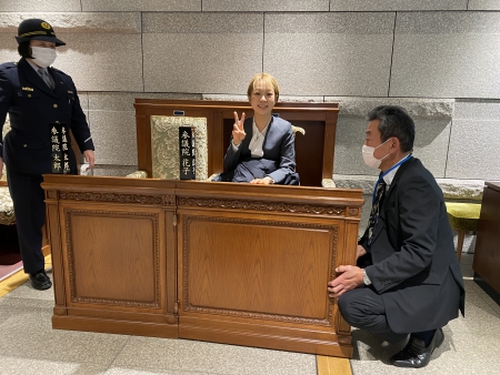 写真：見学コースには本会議場と同じ椅子が展示されていて、車いすでも着席できます。さらに、視覚障害者が手で触れるように国会議事堂や本会議場の模型もありました。